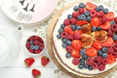 Photo of Delicious chocolate sponge cake with berries served on white wooden table, top view