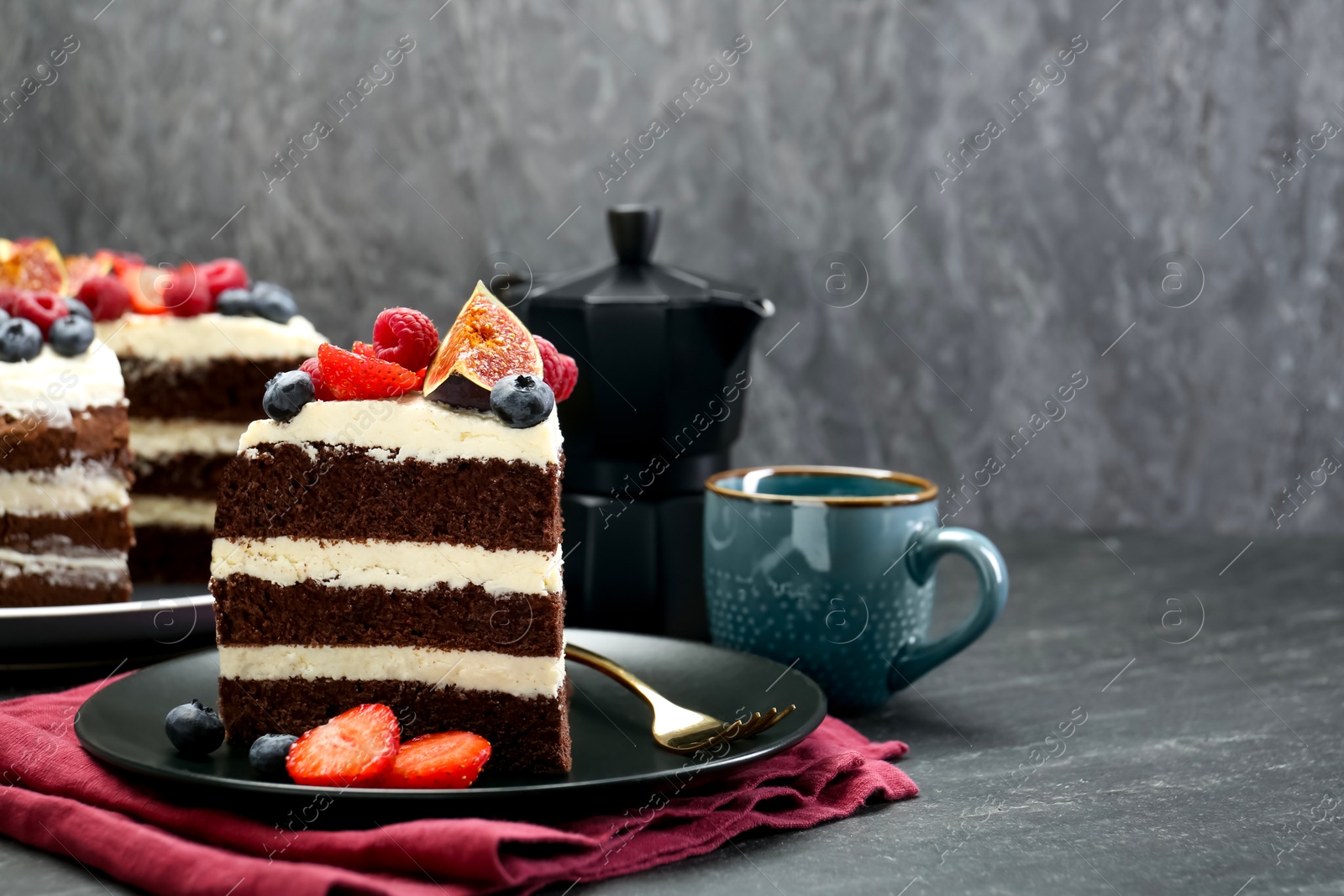 Photo of Piece of delicious chocolate sponge cake with berries on black table