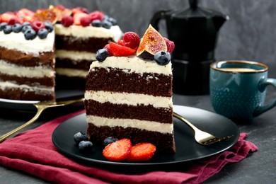 Piece of delicious chocolate sponge cake with berries served on black table, closeup