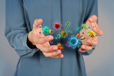 Image of Man showing hands with microbes on grey background, closeup. Illustration of microorganisms