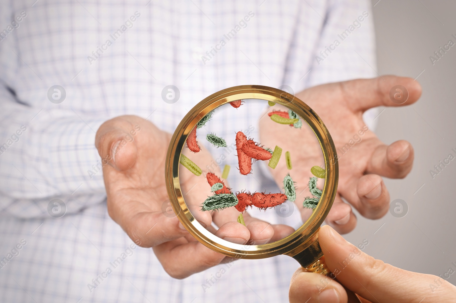 Image of Woman looking at man's hand with magnifying glass, closeup. Illustration of microbes