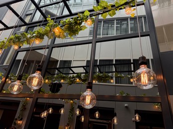 Photo of Light bulbs hanging on cords at outdoor terrace, low angle view