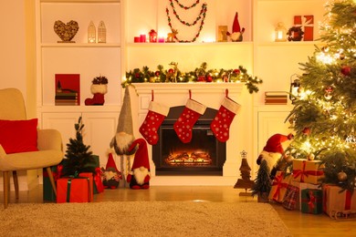 Photo of Stylish fireplace, Christmas tree with festive decor and presents indoors