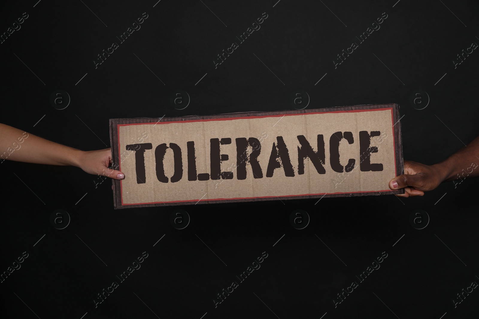 Image of Woman and African American man holding sign with word Tolerance on black background, closeup