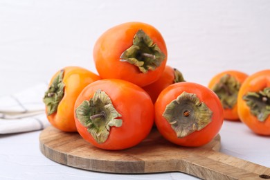 Delicious fresh juicy persimmons on white table, closeup