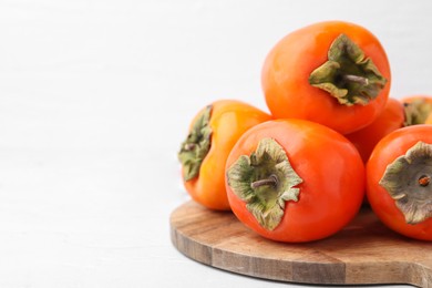 Delicious fresh juicy persimmons on white table, closeup. Space for text