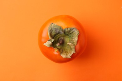 Photo of Delicious fresh juicy persimmon on orange table, top view