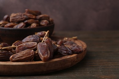 Photo of Tasty dried dates on wooden table, closeup. Space for text