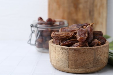 Photo of Tasty dried dates on white tiled table, closeup. Space for text