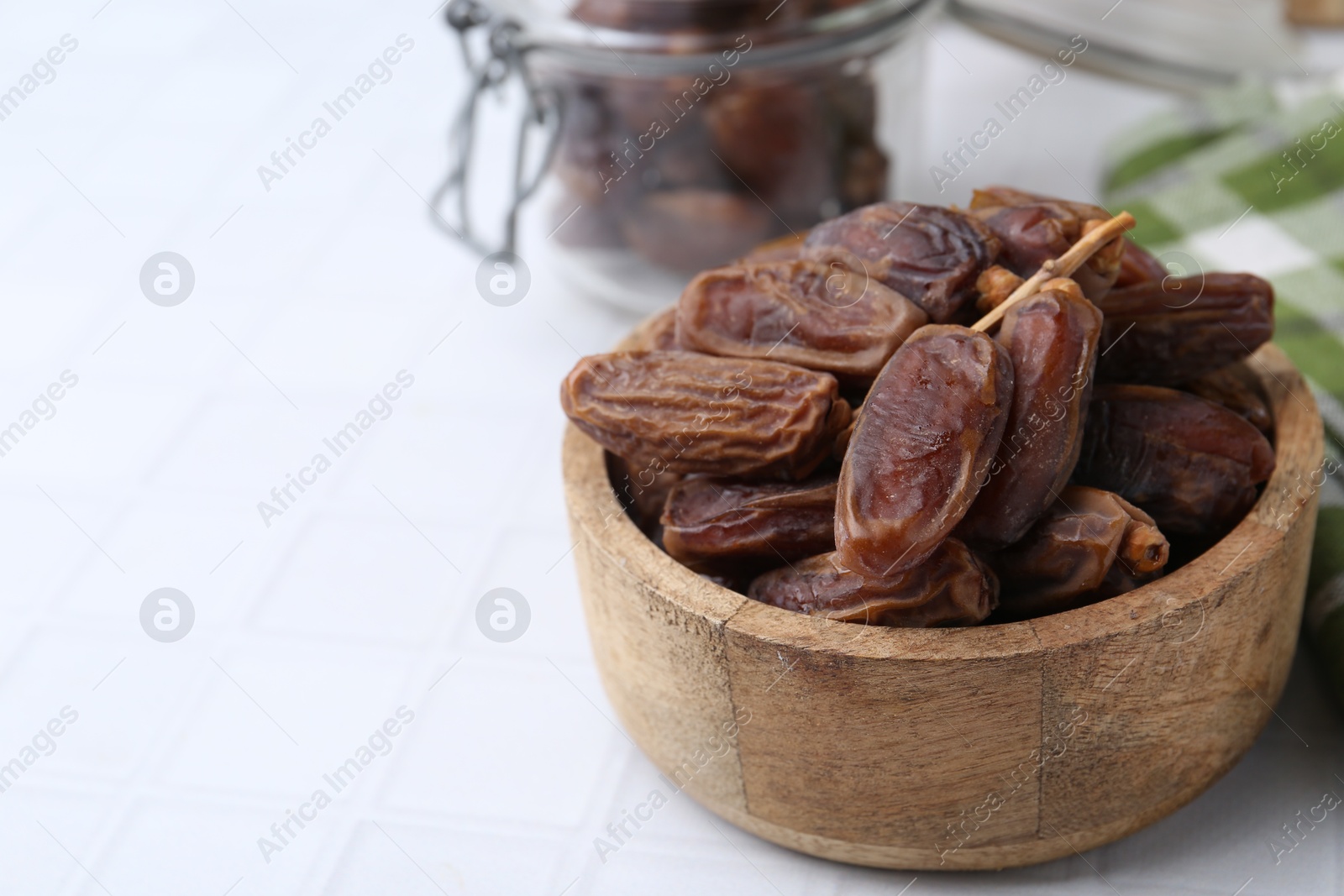 Photo of Tasty dried dates on white tiled table, closeup. Space for text