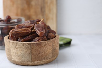 Photo of Tasty dried dates on white tiled table, closeup. Space for text