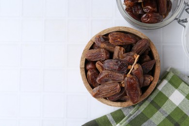 Photo of Tasty dried dates on white tiled table, top view. Space for text