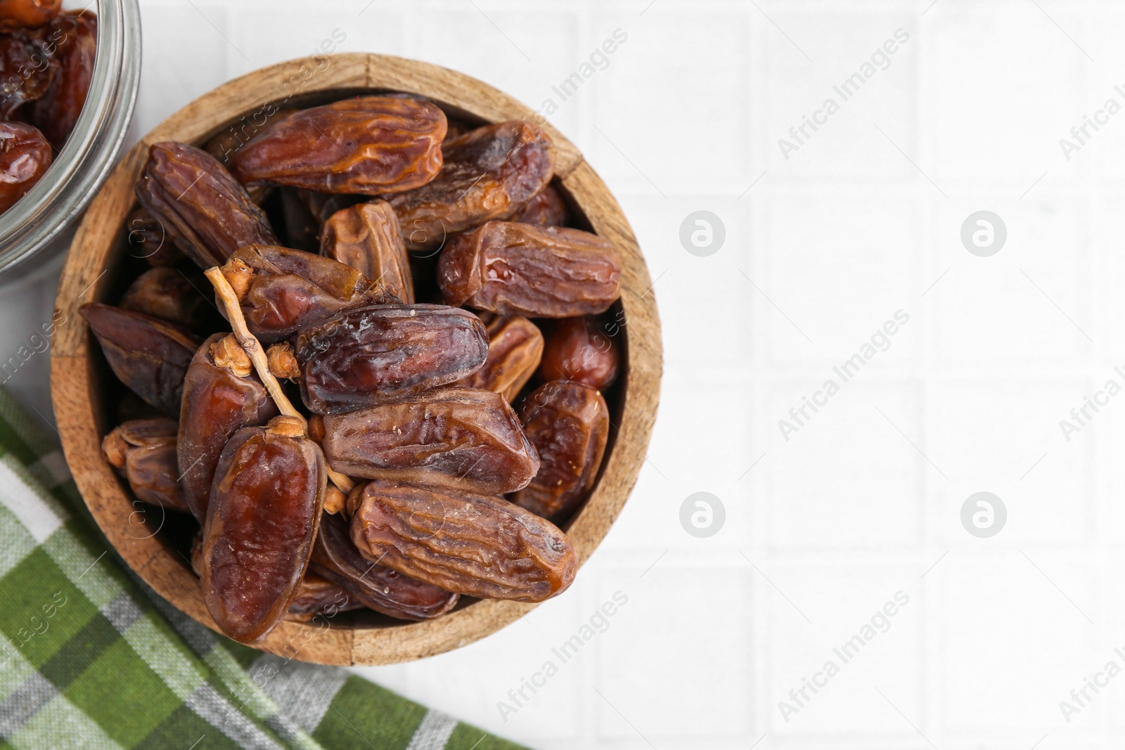 Photo of Tasty dried dates on white tiled table, top view. Space for text