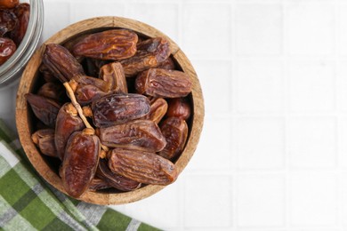 Photo of Tasty dried dates on white tiled table, top view. Space for text