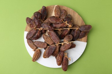 Photo of Tasty dried dates on green background, top view