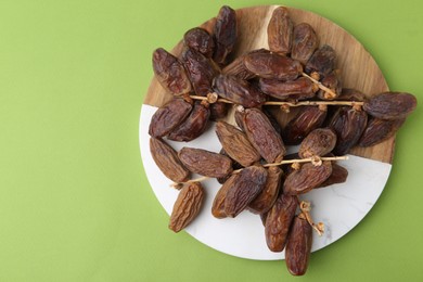 Photo of Tasty dried dates on green background, top view