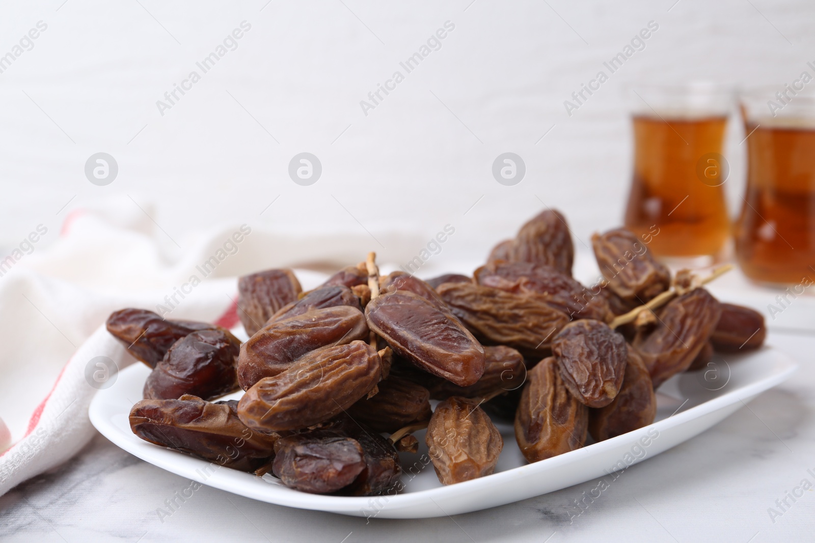 Photo of Tasty dried dates and tea on white marble table, closeup