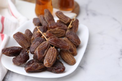 Photo of Tasty dried dates and tea on white marble table, closeup