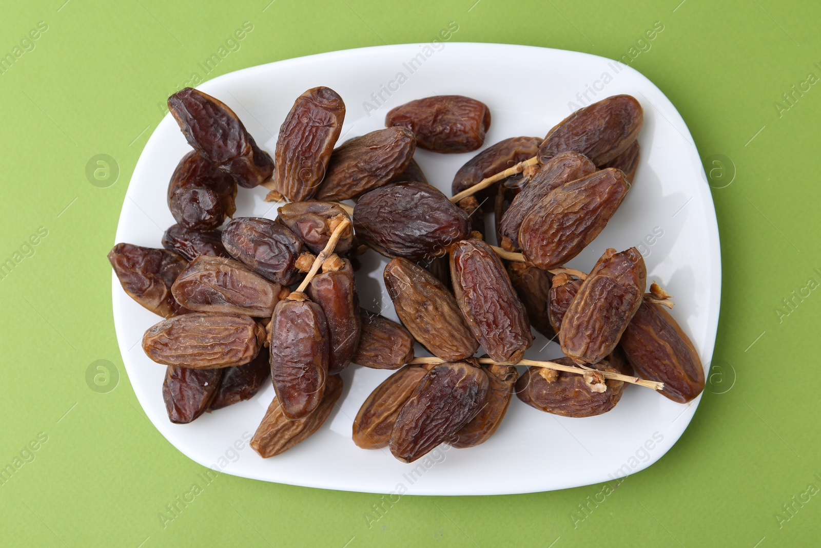 Photo of Tasty dried dates on green background, top view