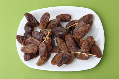 Photo of Tasty dried dates on green background, top view