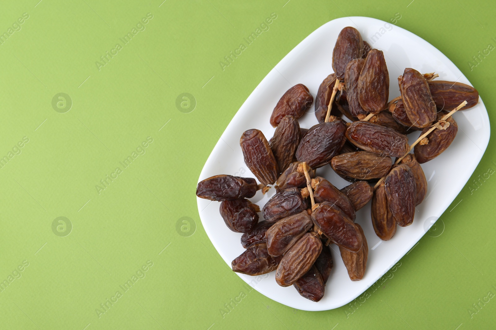 Photo of Tasty dried dates on green background, top view. Space for text