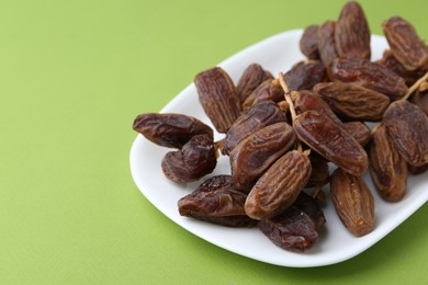 Photo of Tasty dried dates on green background, closeup. Space for text