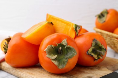 Photo of Whole and cut ripe persimmons on table, closeup