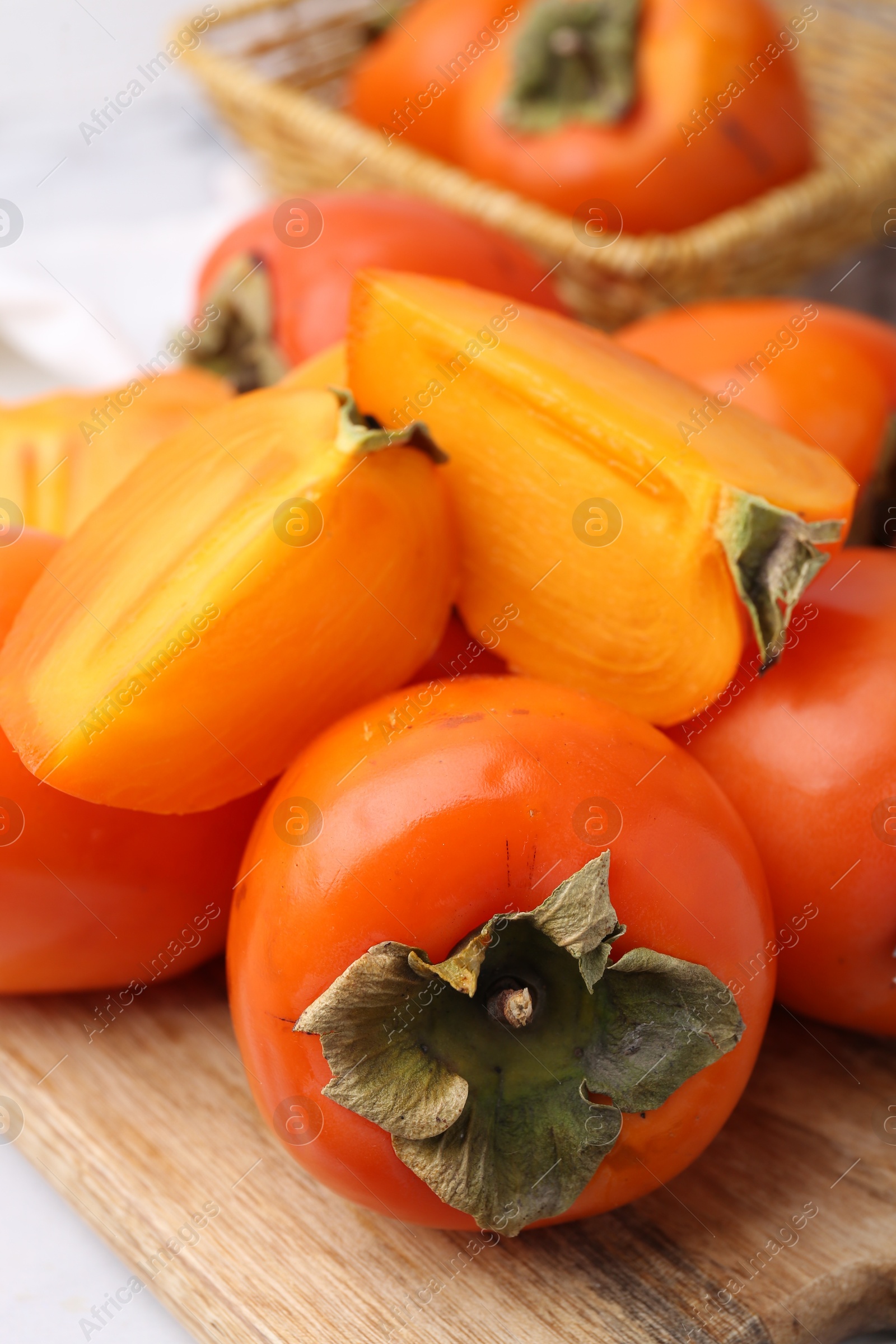 Photo of Whole and cut ripe persimmons on table, closeup