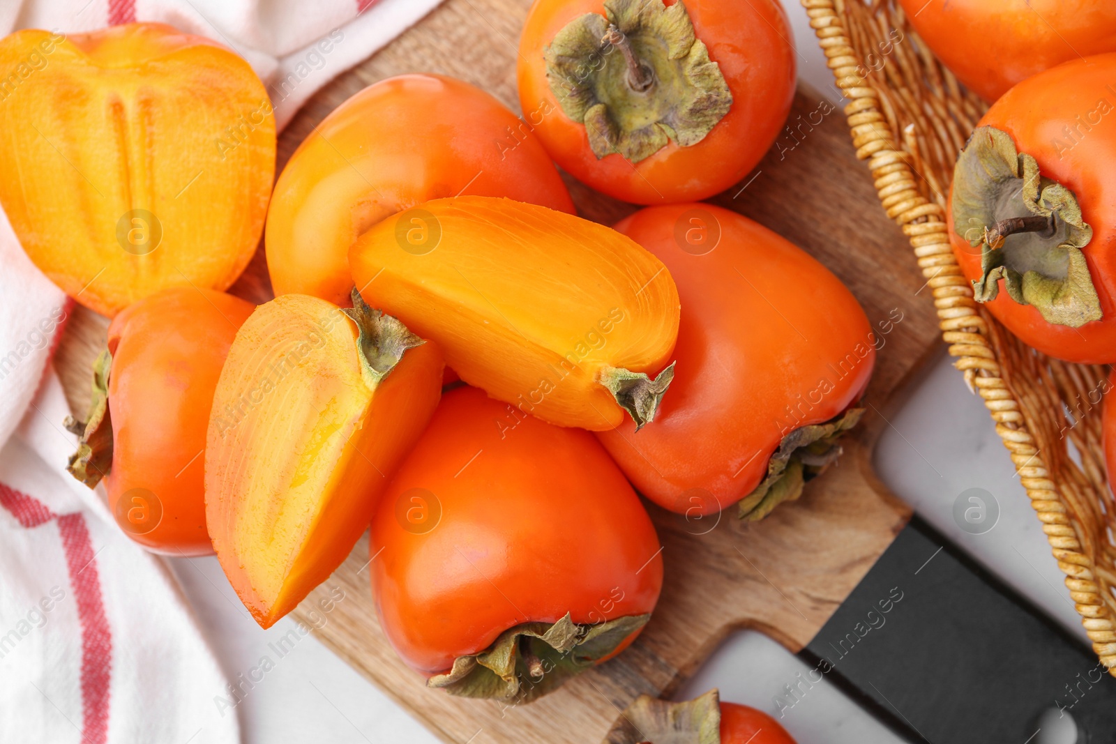 Photo of Whole and cut ripe persimmons on white table, flat lay