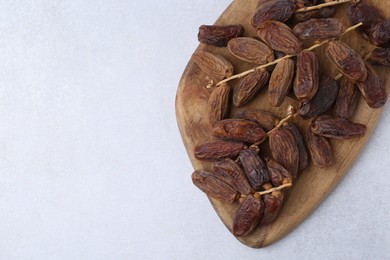 Photo of Tasty dried dates on light table, top view. Space for text