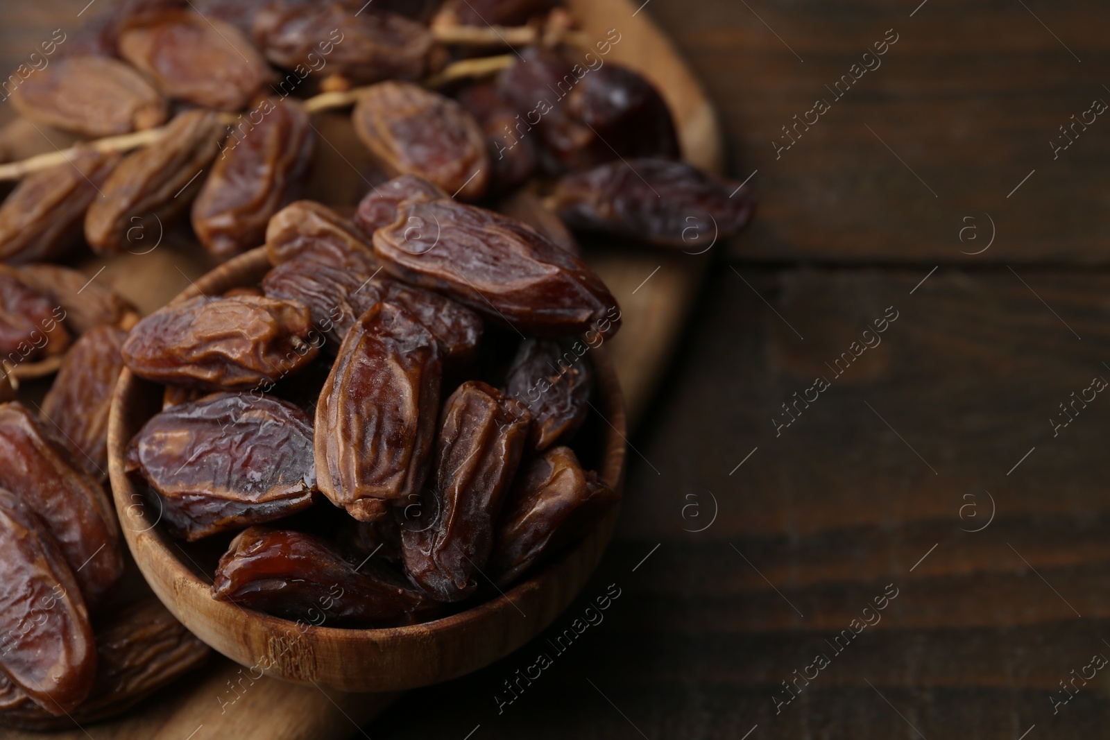 Photo of Tasty dried dates on wooden table, closeup. Space for text