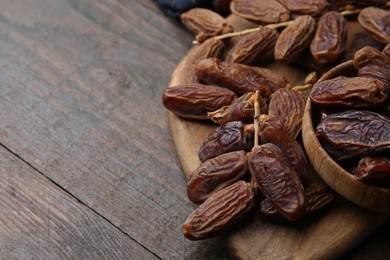 Photo of Tasty dried dates on wooden table, closeup. Space for text