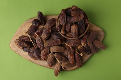 Photo of Tasty dried dates on green background, top view