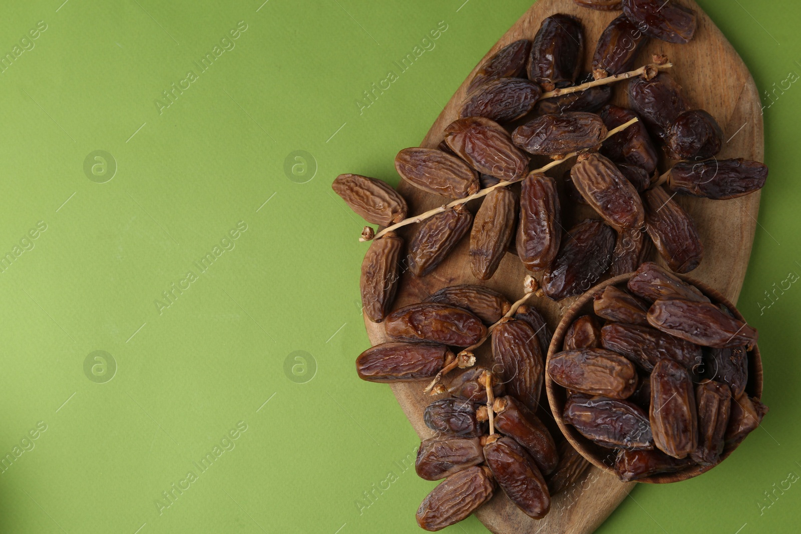 Photo of Tasty dried dates on green background, top view. Space for text