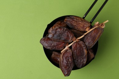 Photo of Tasty dried dates on green background, top view