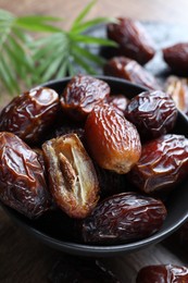 Photo of Tasty dried dates and leaves on wooden table, closeup