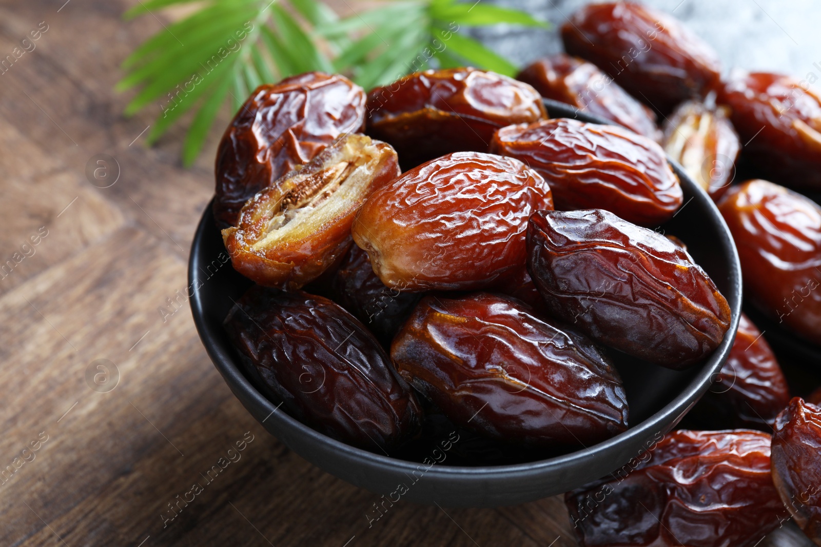 Photo of Tasty dried dates and leaves on wooden table, closeup