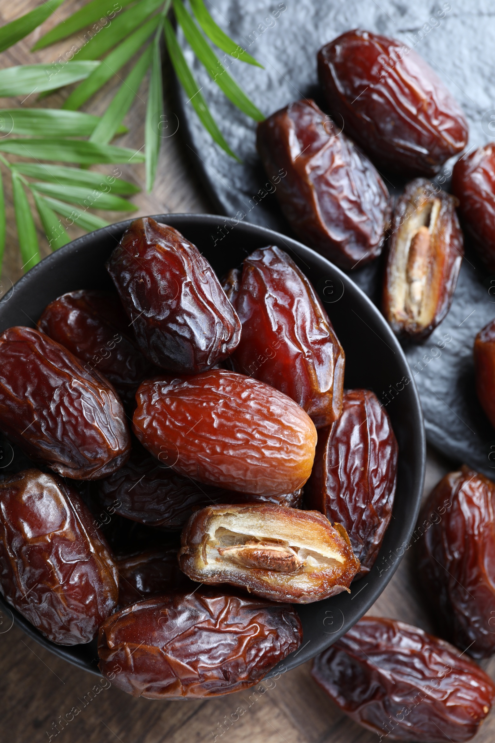 Photo of Tasty dried dates and leaves on wooden table, flat lay