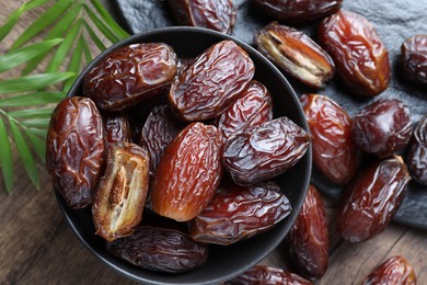 Photo of Tasty dried dates and leaves on wooden table, flat lay