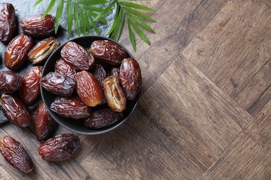 Photo of Tasty dried dates and leaves on wooden table, flat lay. Space for text