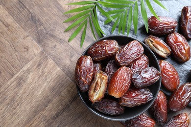 Photo of Tasty dried dates and leaves on wooden table, flat lay. Space for text