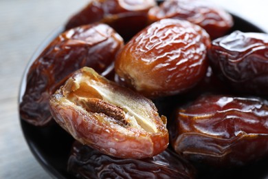 Photo of Many tasty dried dates in bowl on table, closeup