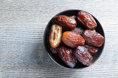 Photo of Tasty dried dates on light wooden table, top view. Space for text