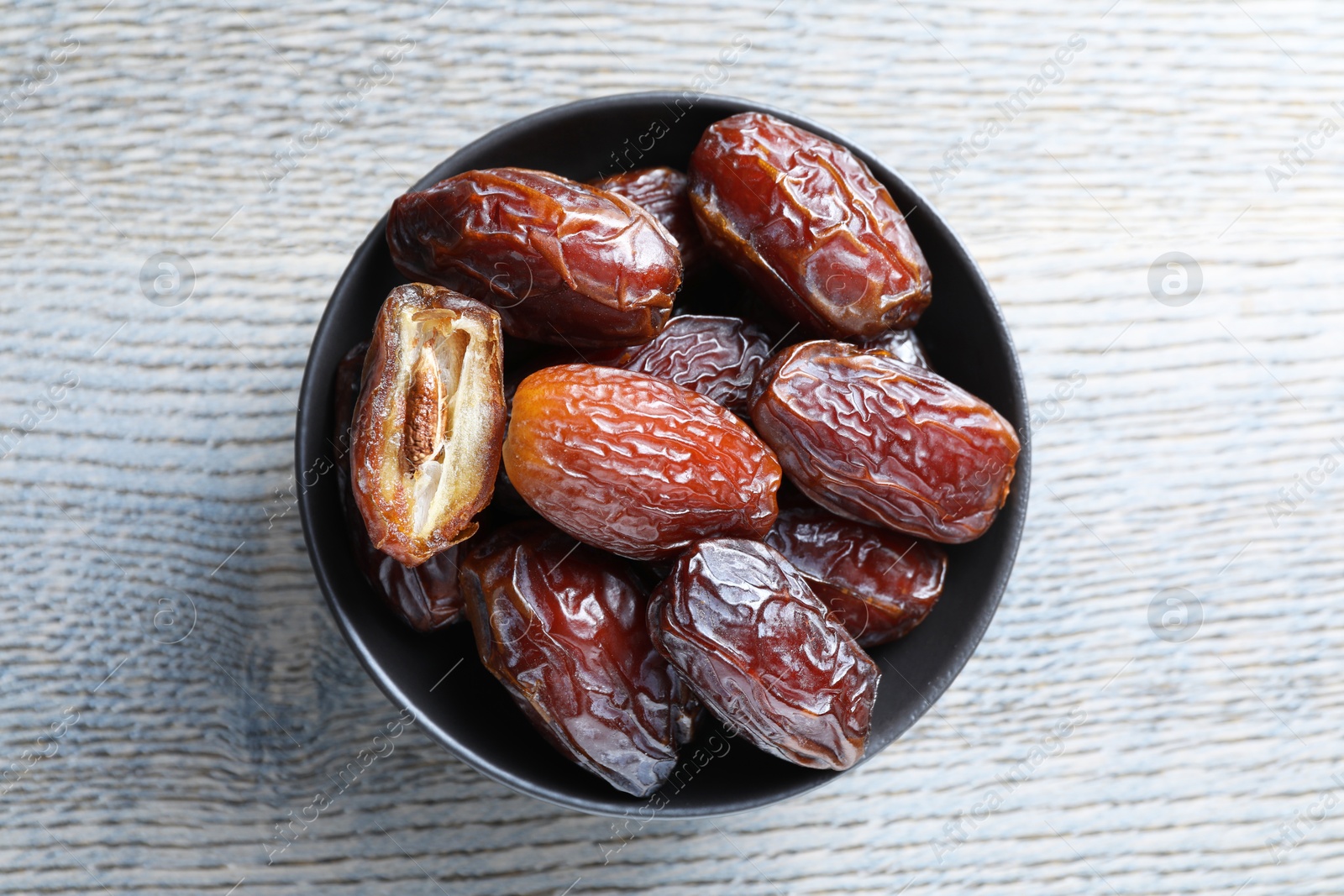 Photo of Tasty dried dates on light wooden table, top view