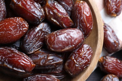 Photo of Many tasty dried dates in bowl on table, closeup