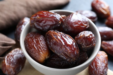 Photo of Many tasty dried dates in bowl on table, closeup