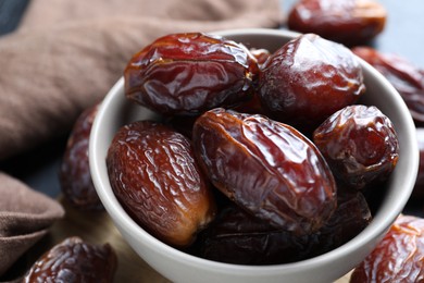 Photo of Many tasty dried dates in bowl on table, closeup