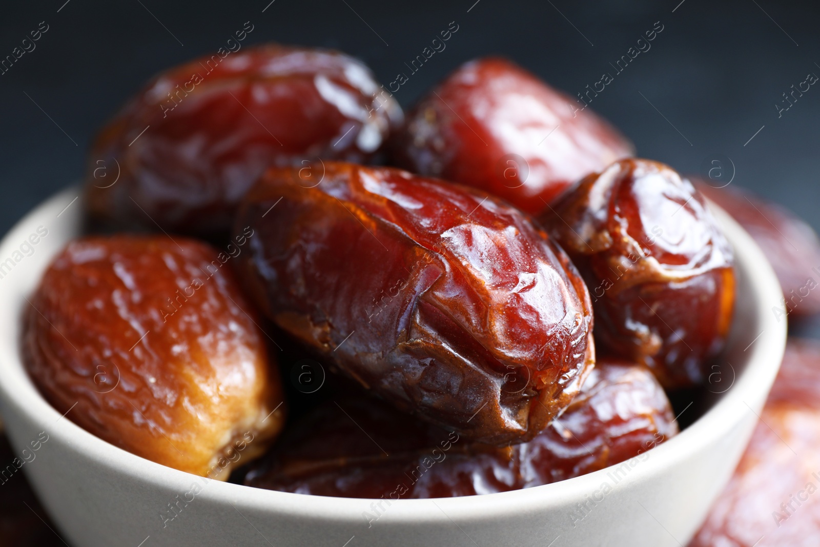 Photo of Many tasty dried dates in bowl, closeup