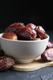 Photo of Tasty dried dates in bowl on grey table