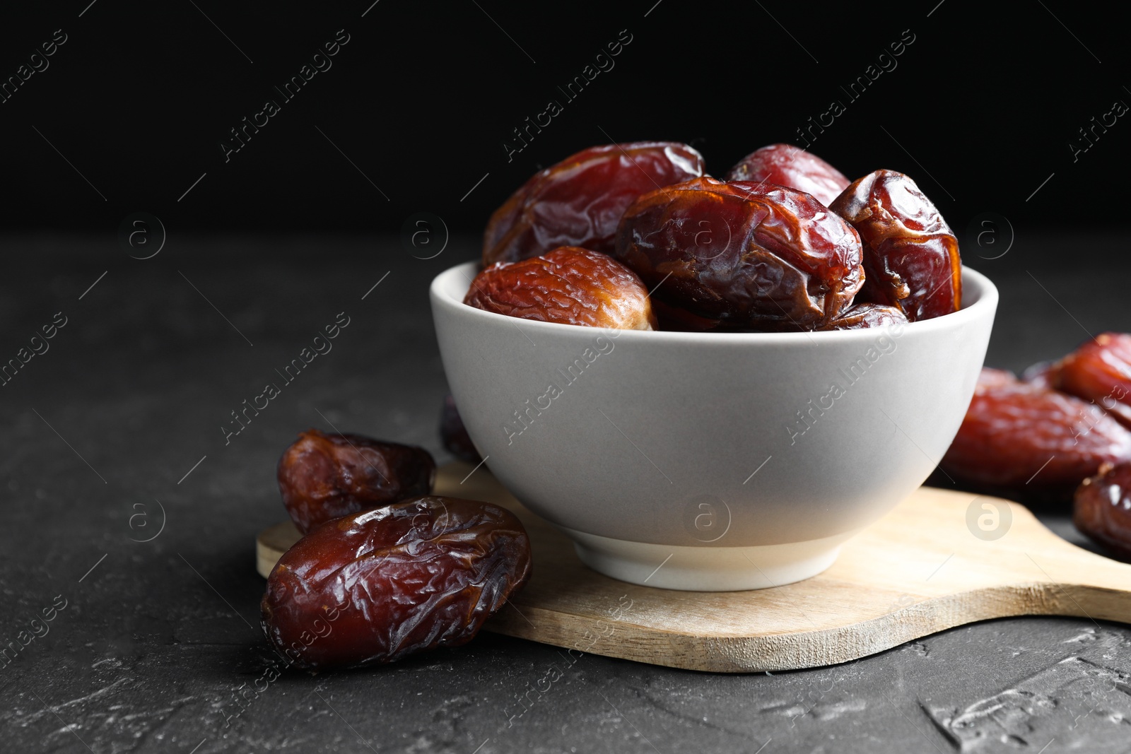 Photo of Tasty dried dates in bowl on grey table